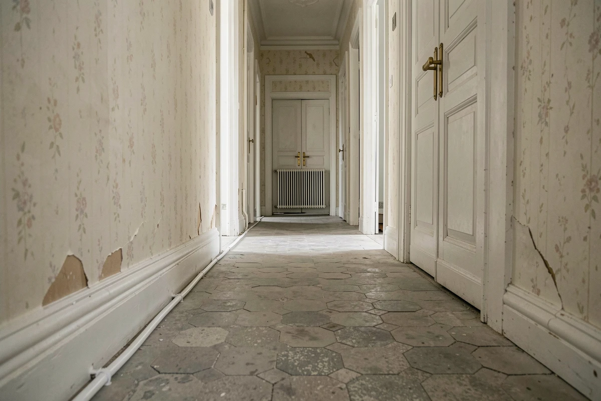 Couloir d'appartement ancien avec câble électrique en goulotte menant à un radiateur électrique au mur