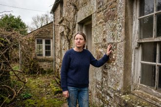 Femme d'âge moyen touchant une vieille maison en pierre